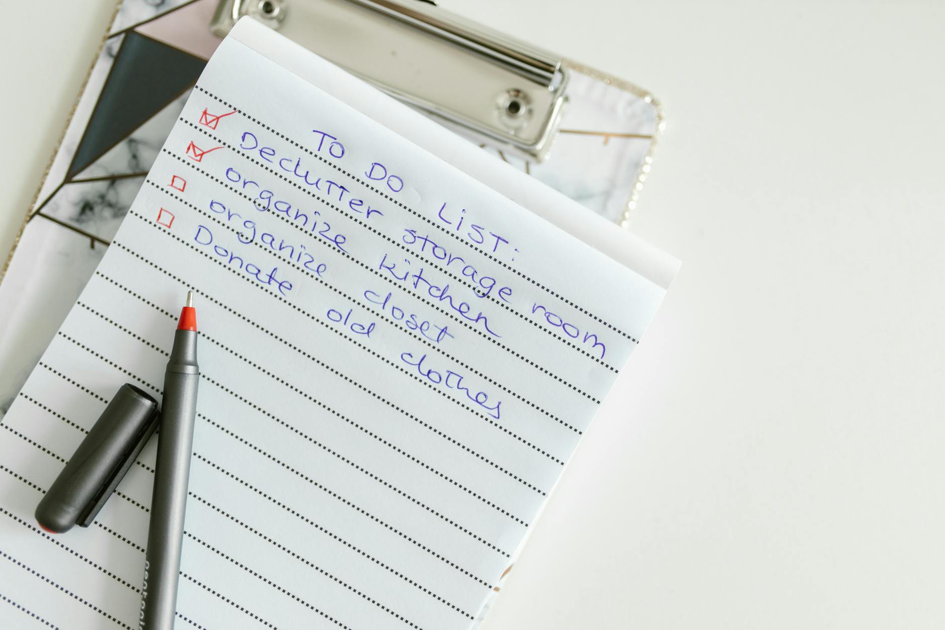 Handwritten to-do list on a clipboard with declutter and organize items, two checked off, and a pen