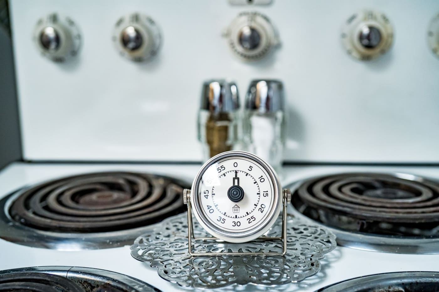 Analog kitchen timer sitting on an electric stovetop
