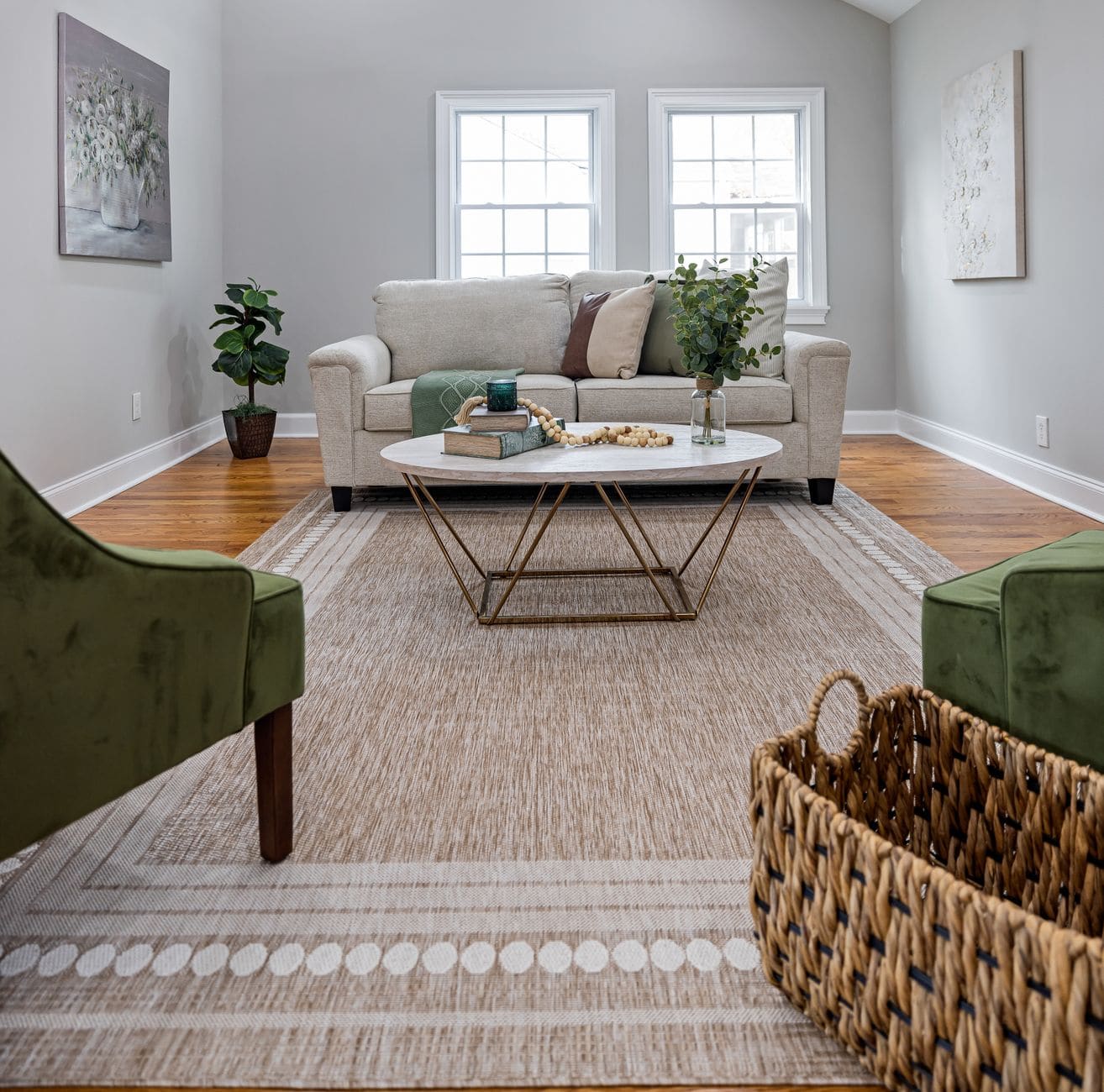 Living room with a light sofa, a round glass coffee table with a few items and a woven rug